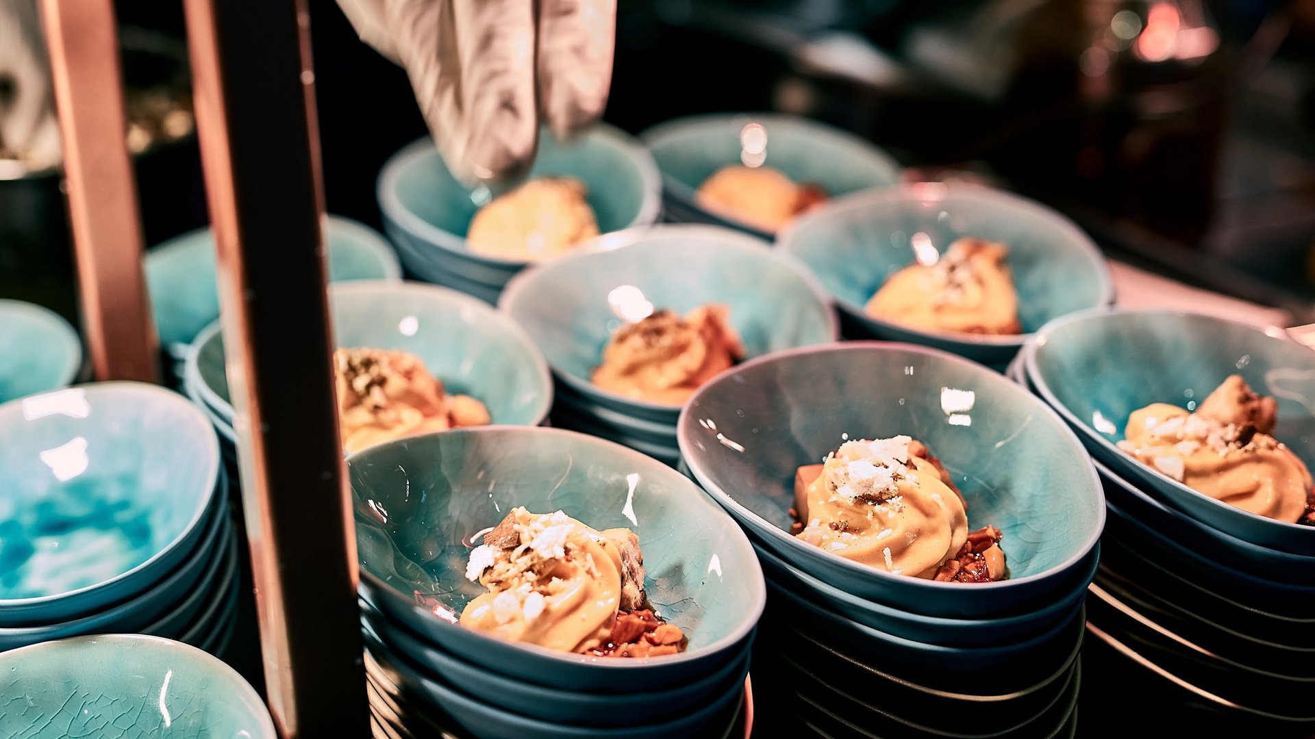 Ice cream with toppings in blue bowls, being hand-decorated in a restaurant