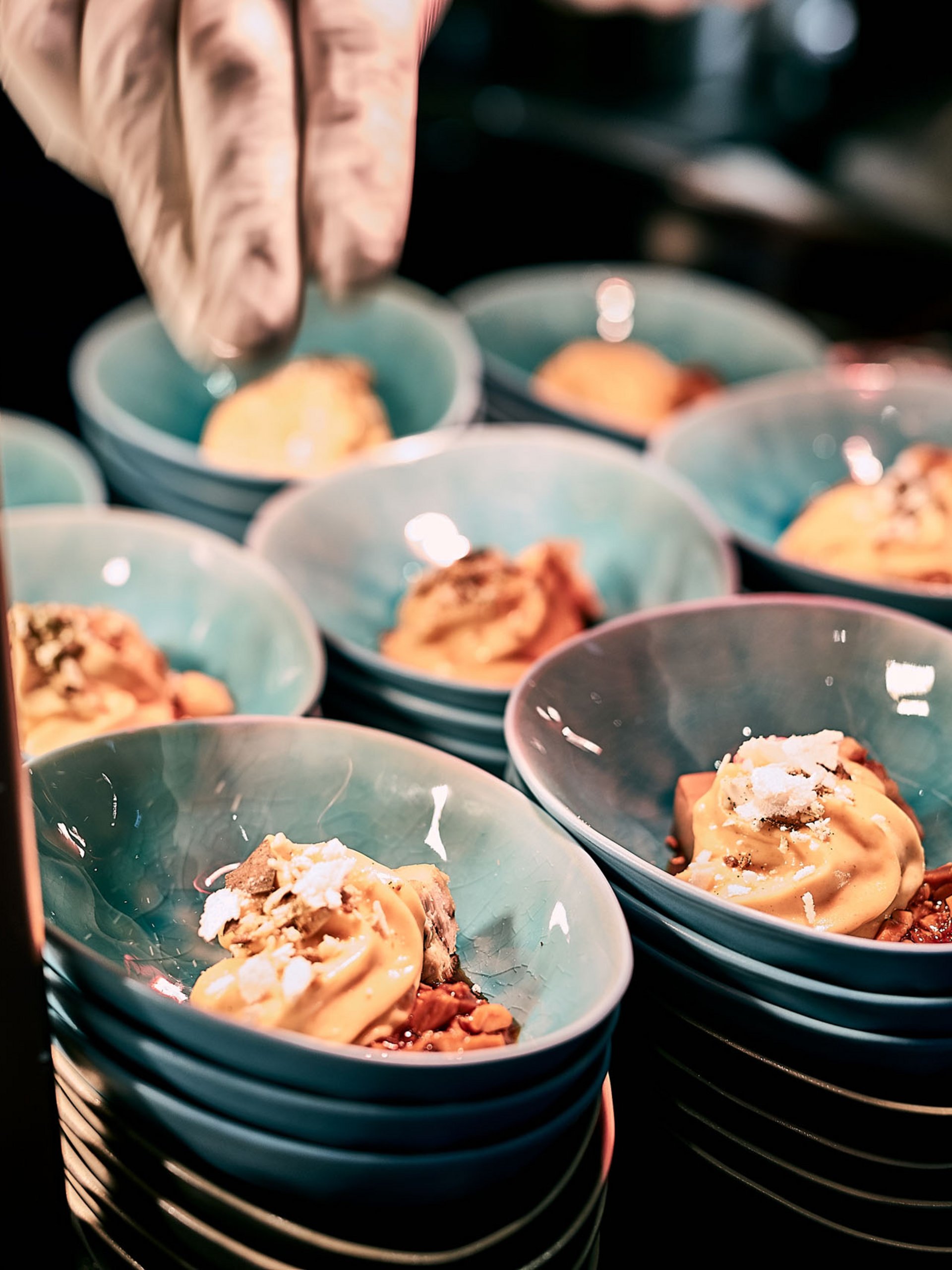 Ice cream with toppings in blue bowls, being hand-decorated in a restaurant