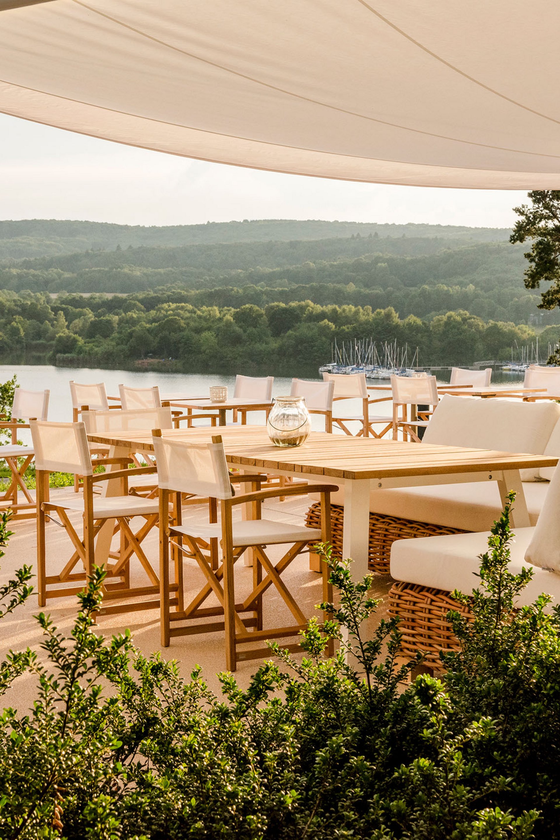 Sunny terrace with white chairs and lake view under a canopy