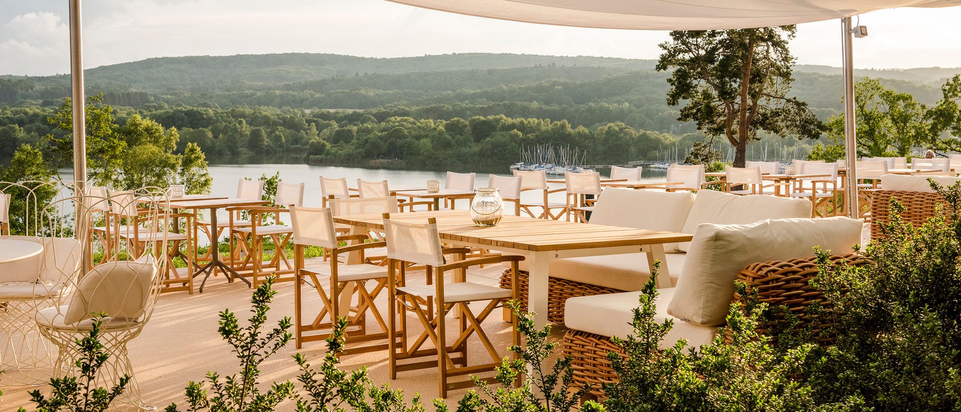 Terrasse ensoleillée avec chaises blanches et vue sur le lac sous un auvent