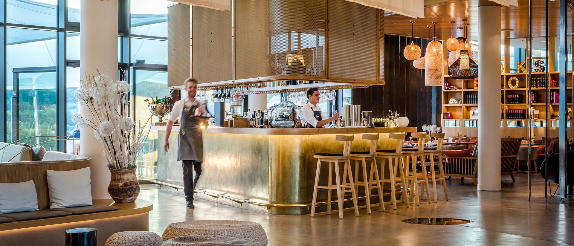 Bar d'hôtel moderne avec comptoir en laiton et personnel