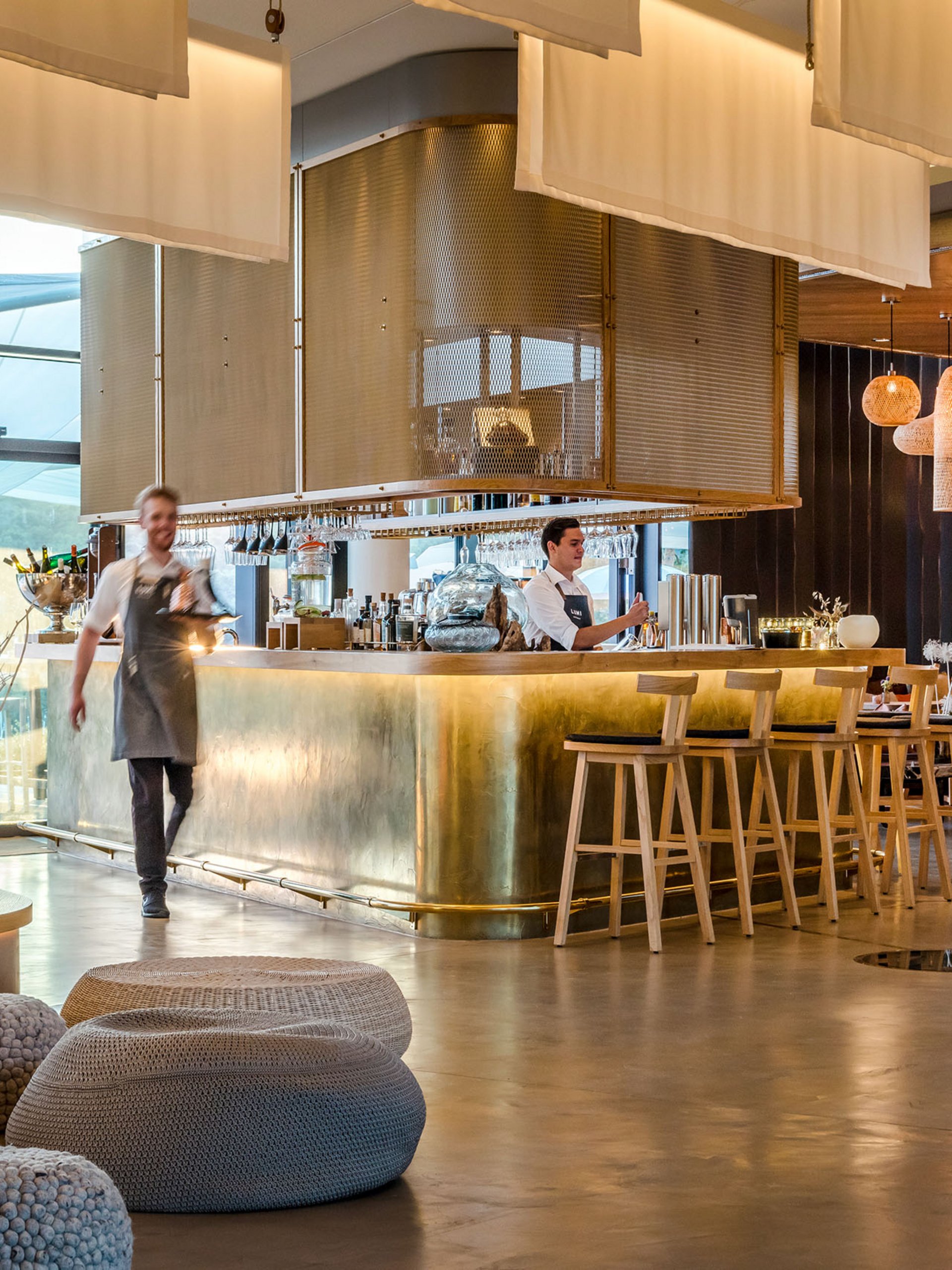 Moderner Hotelbarbereich mit Bartresen aus Messing und Mitarbeitern