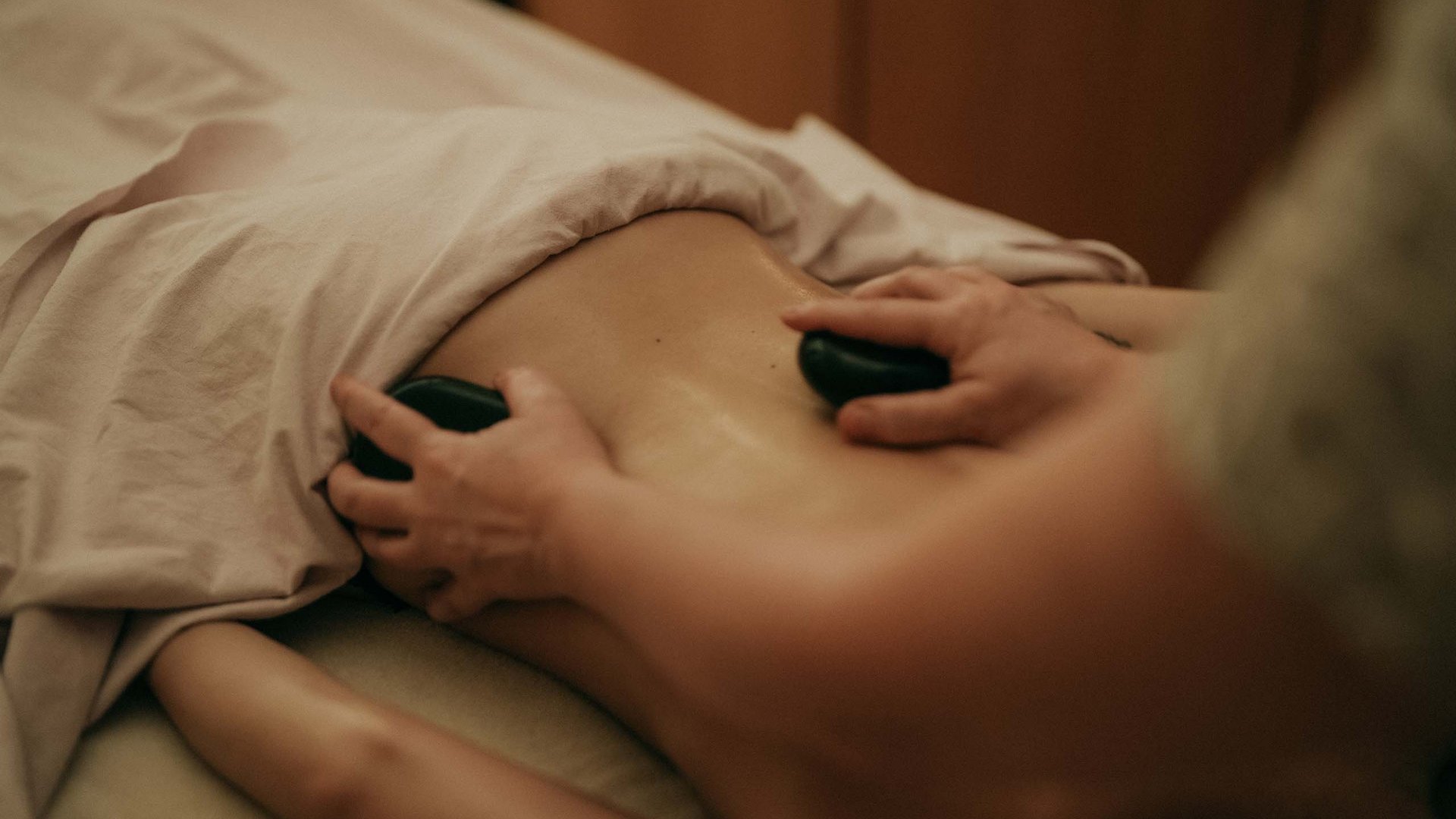 Hot-Stone-Massage mit zwei warmen Steinen auf dem Rücken
