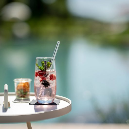 Erfrischendes Getränk mit Beeren und Minze auf einem weißen Tisch am Wasser
