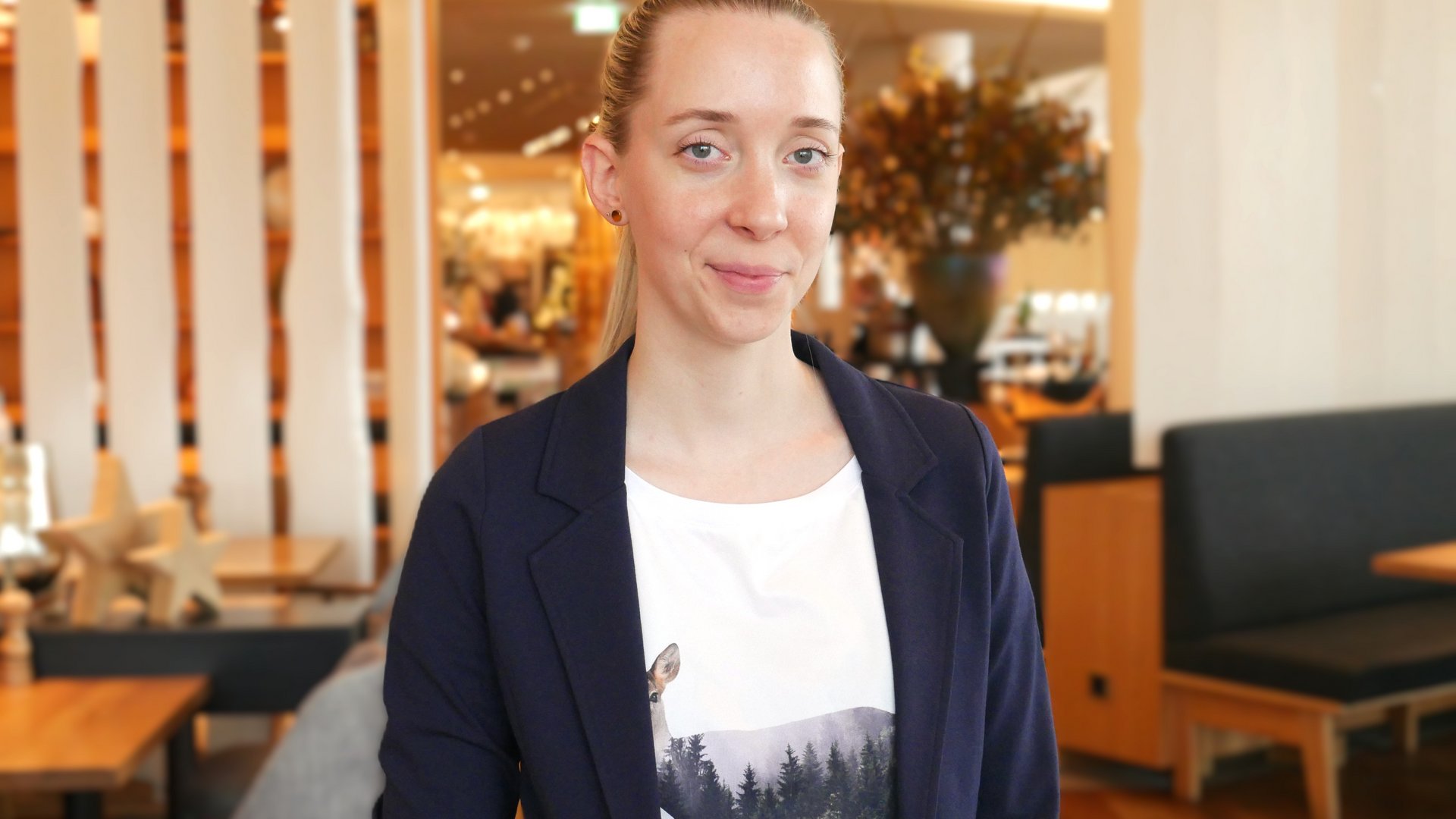 Frau lächelt in die Kamera, im Hintergrund ist ein Restaurant