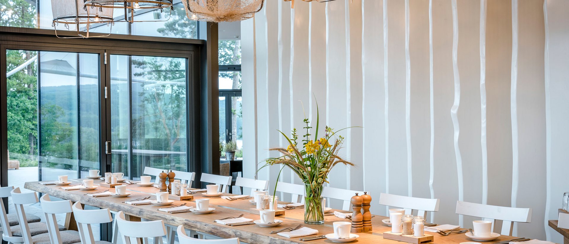 Grande table à manger avec chaises blanches et luminaires modernes dans une pièce lumineuse