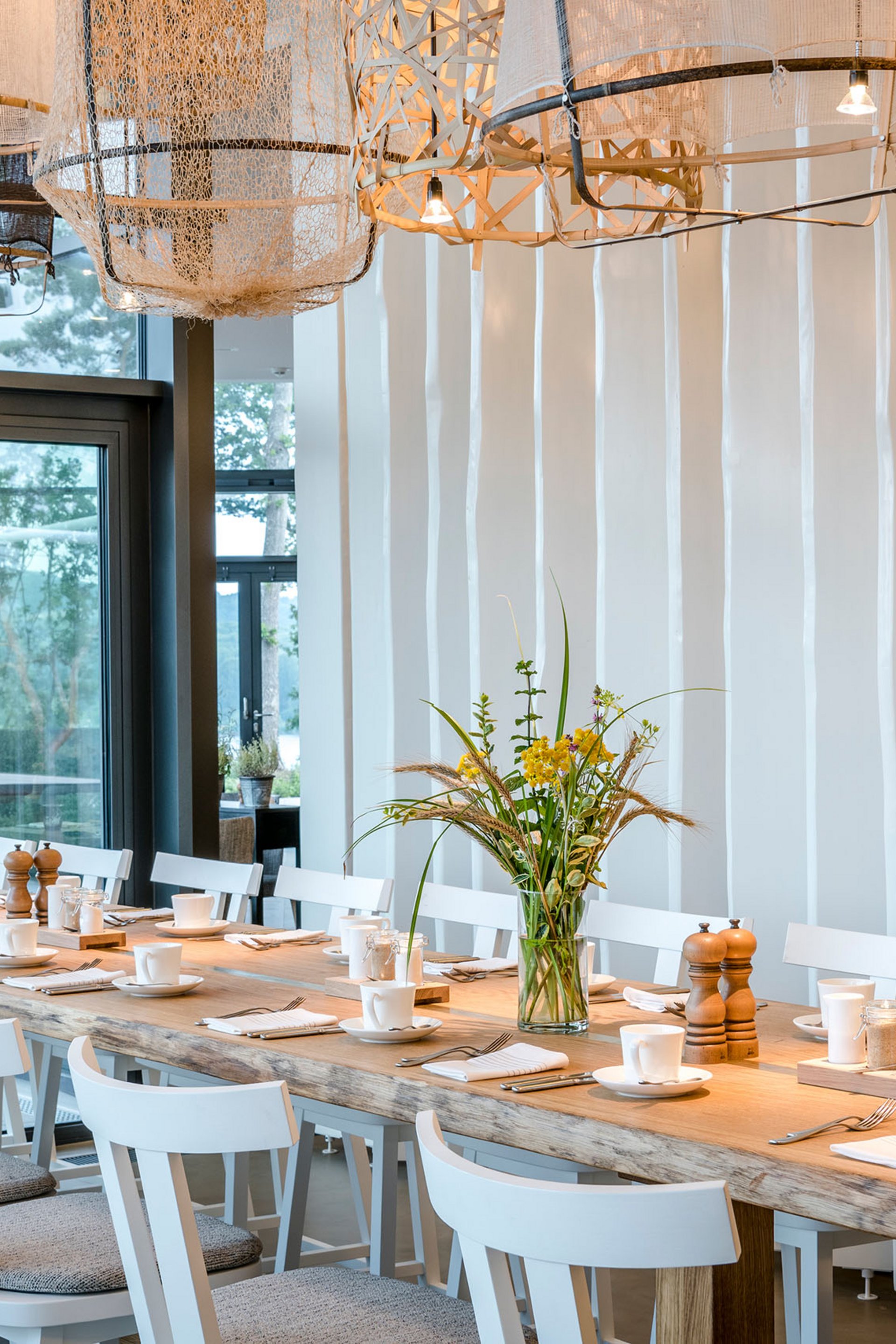 Large dining table with white chairs and modern lights in a bright room