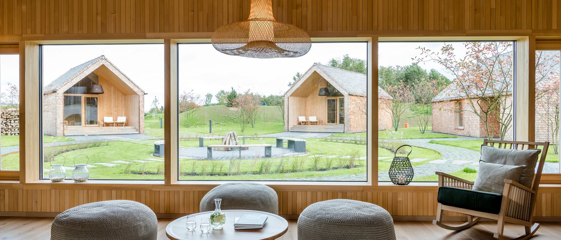 Modernes Wohnzimmer mit großen Fenstern und Blick auf Garten und Häuser