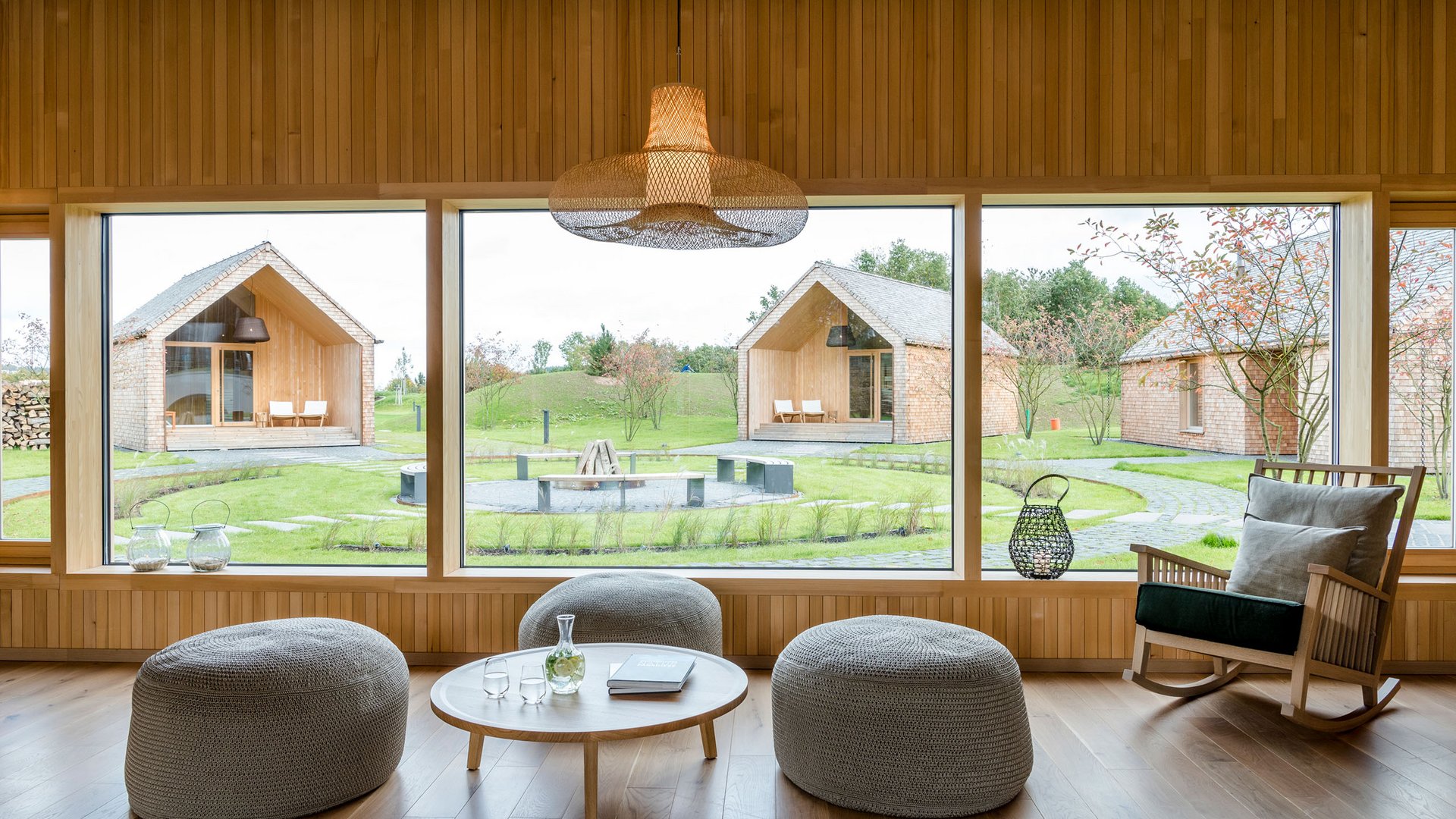 Modernes Wohnzimmer mit großen Fenstern und Blick auf Garten und Häuser