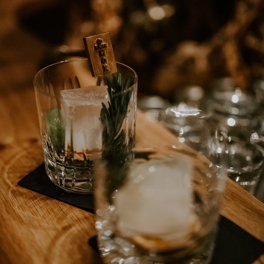Two glasses with large ice cubes and herbs on wooden table