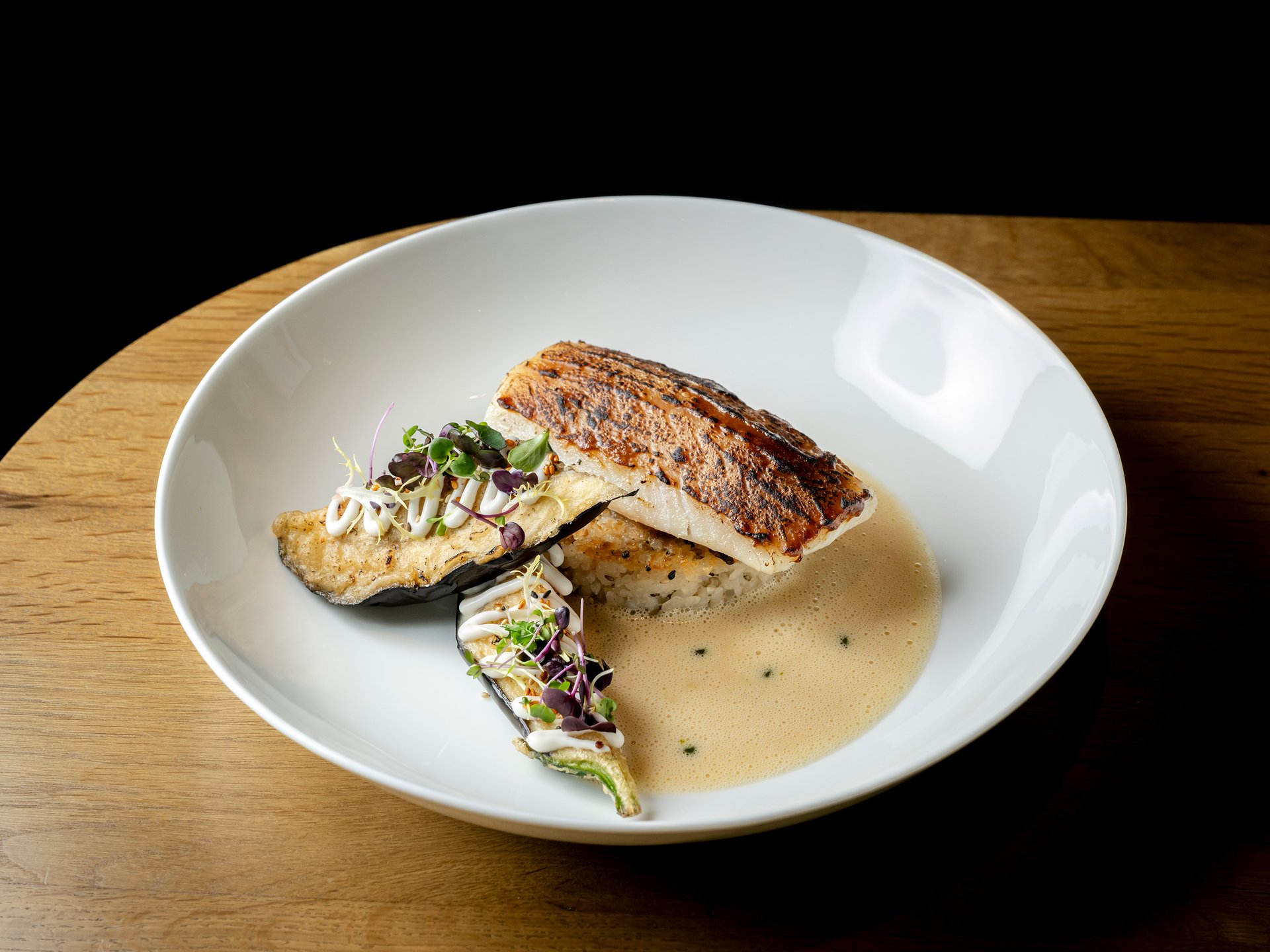Gebratenes Fischfilet mit Gemüse und Sauce auf weißem Teller