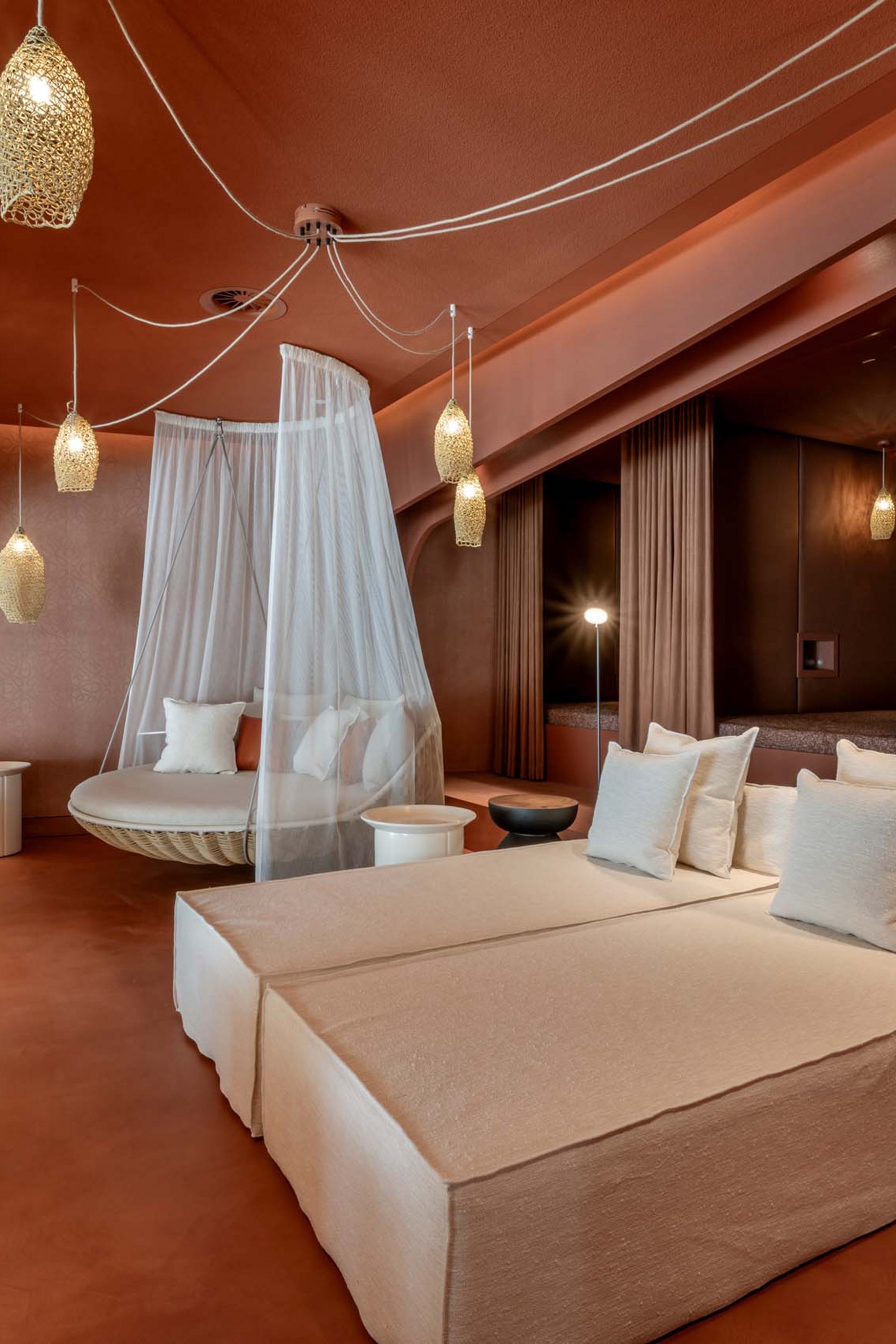 Modern lounge with beige sofas, hanging net chair, and warm lighting
