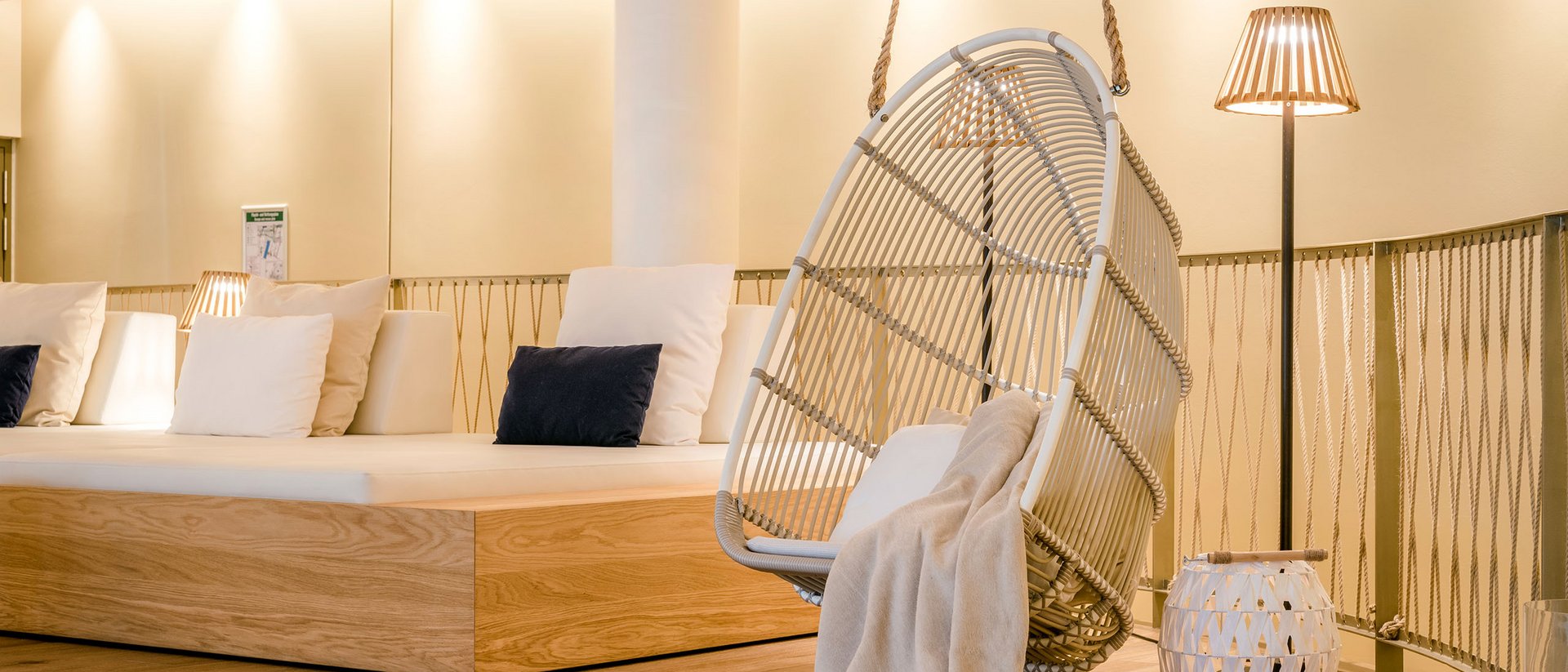 Gemütlicher Lounge-Bereich mit Hängesessel, Kissen und Stehleuchte