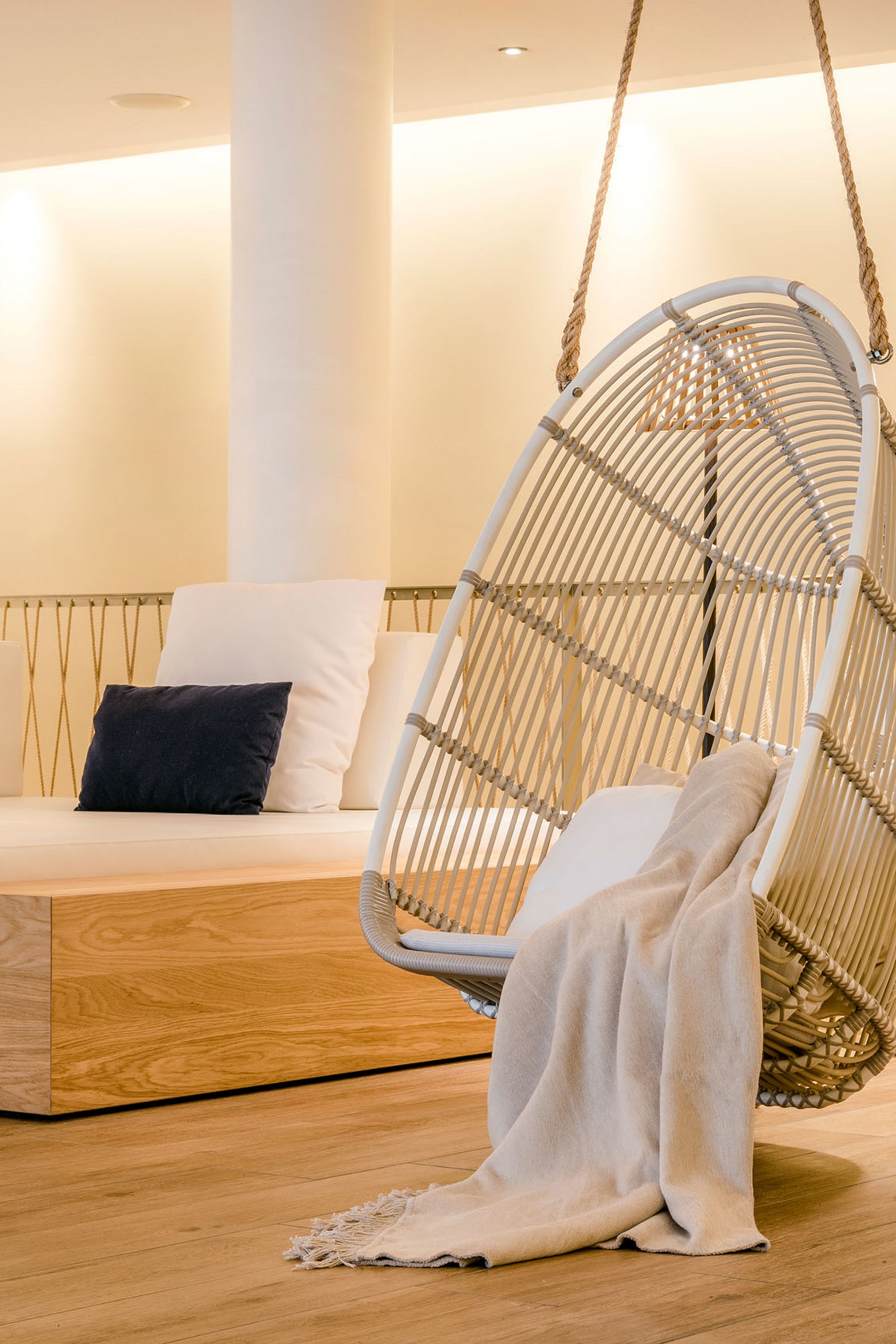 Espace lounge confortable avec fauteuil suspendu, coussins et lampe sur pied