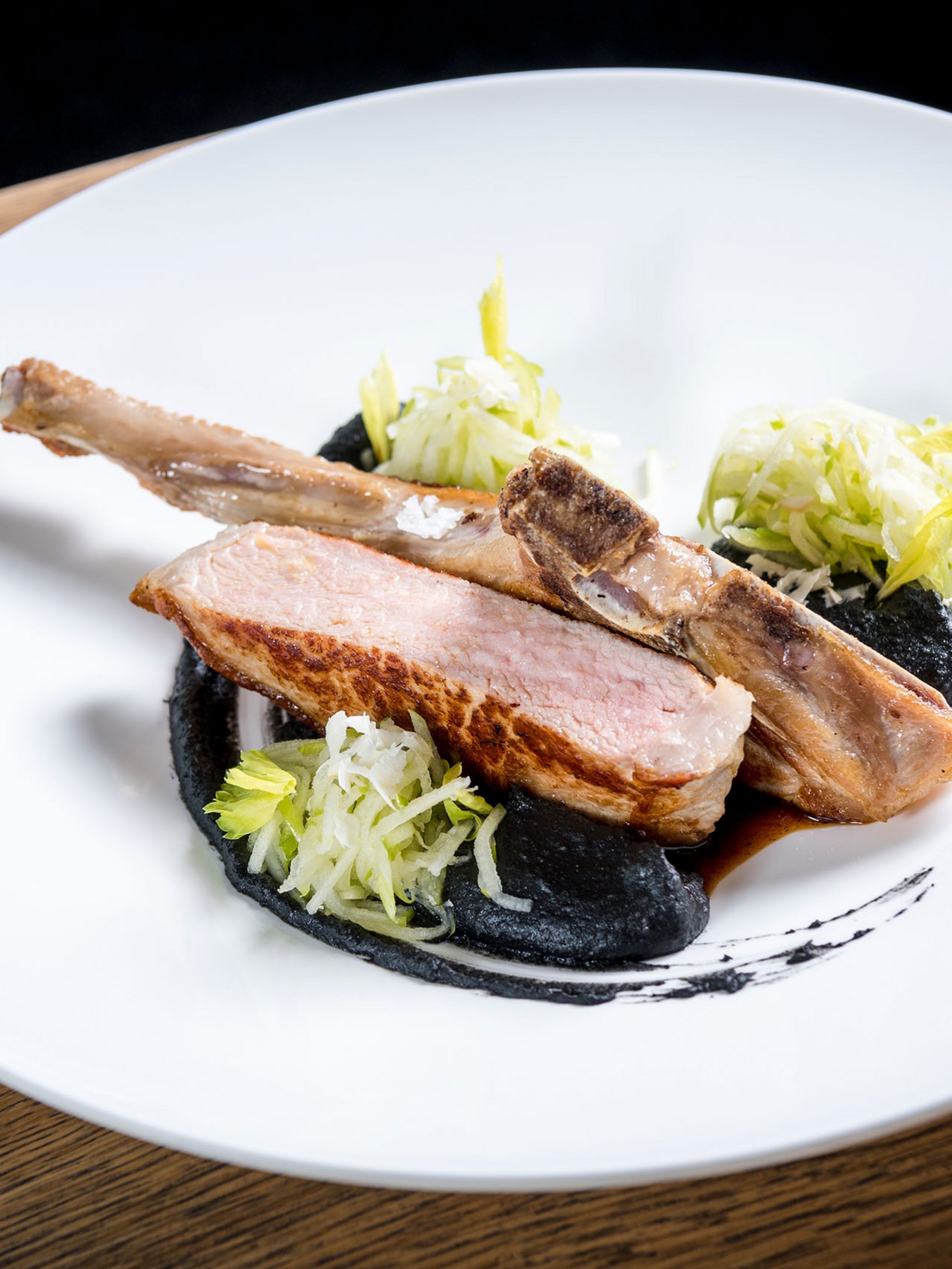 Gebratenes Lammkotelett mit schwarzer Sauce, Salat und Rotwein im Glas