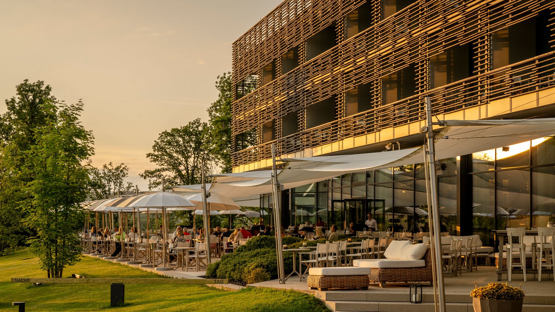 Terrasse ensoleillée d'un restaurant moderne avec des clients au coucher du soleil