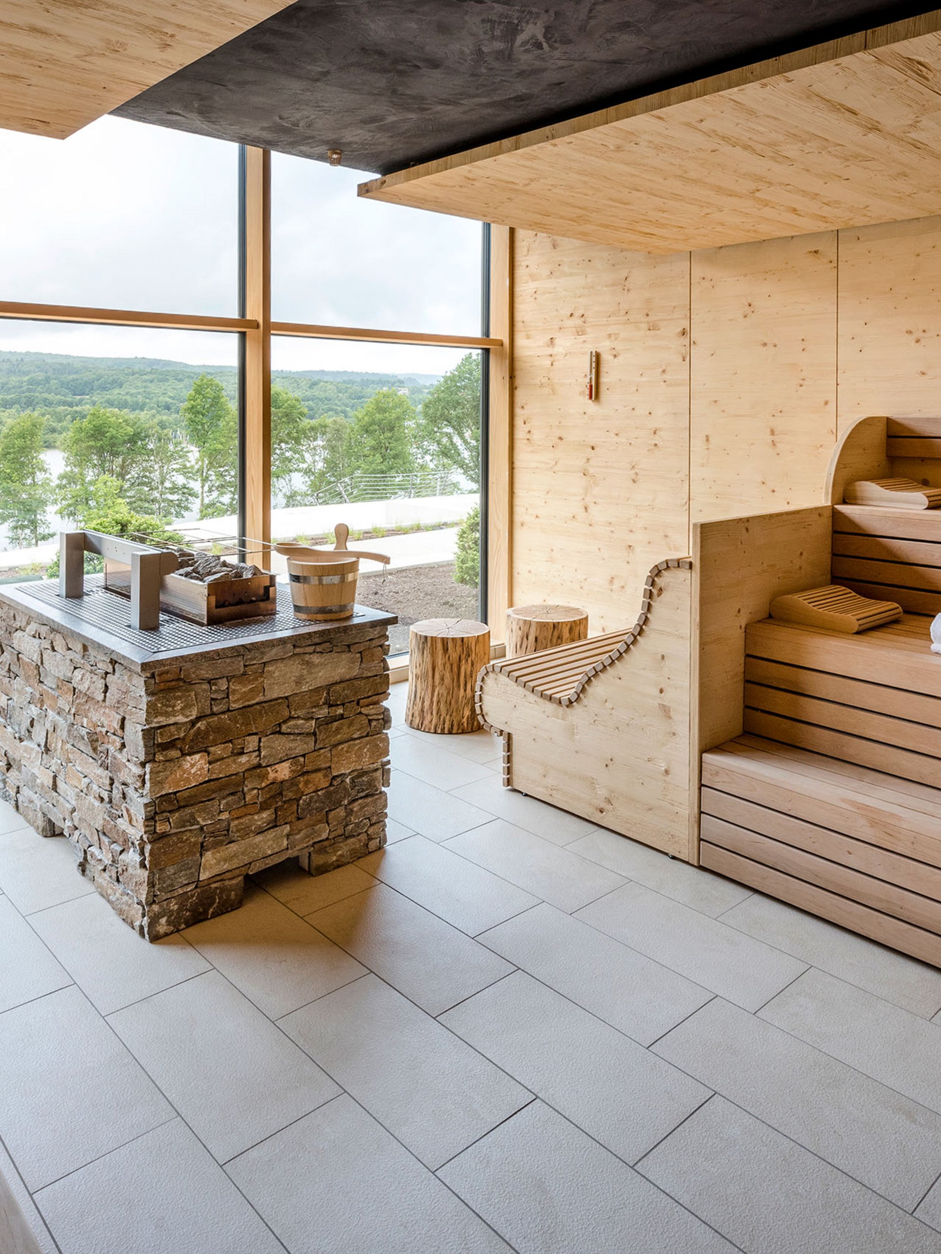 Modern wooden sauna with large window overlooking green landscape