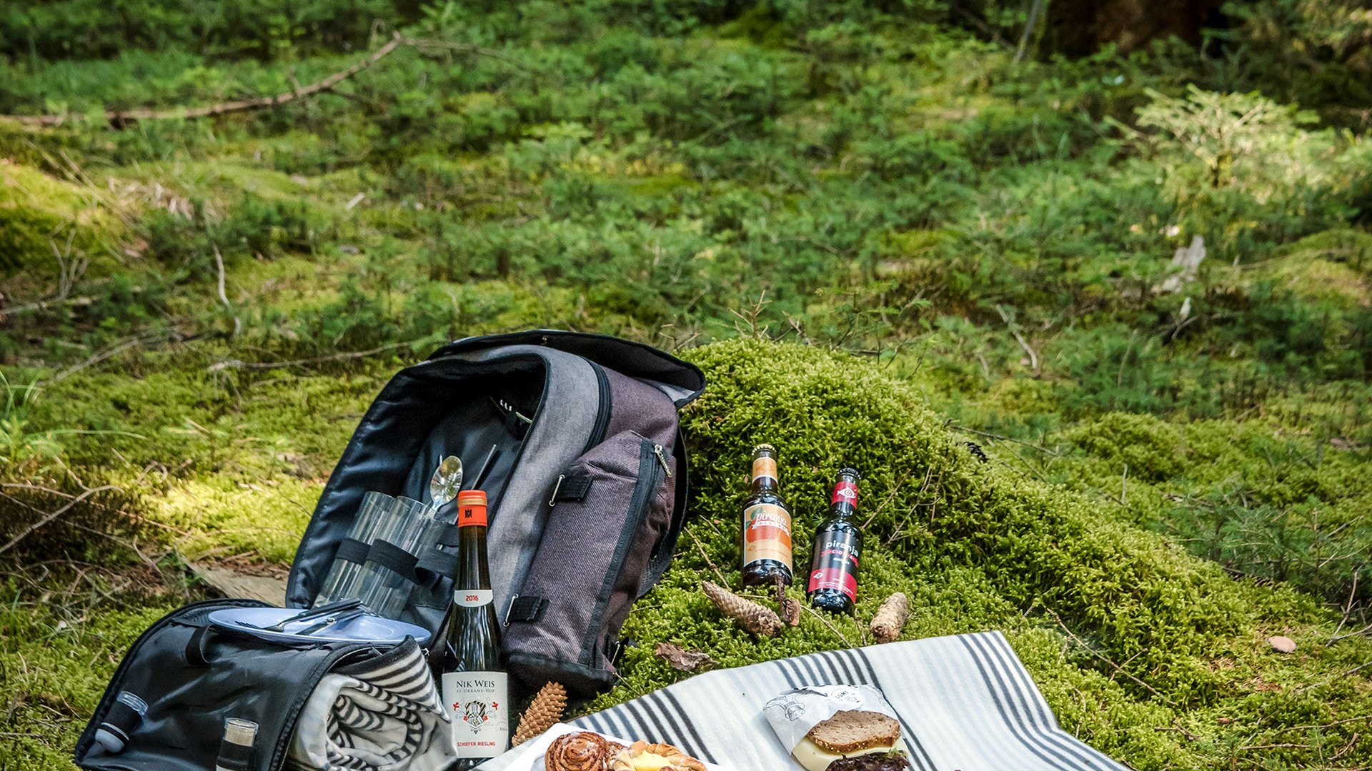 Picknick mit Essen und Getränken auf einer Decke im grünen Wald