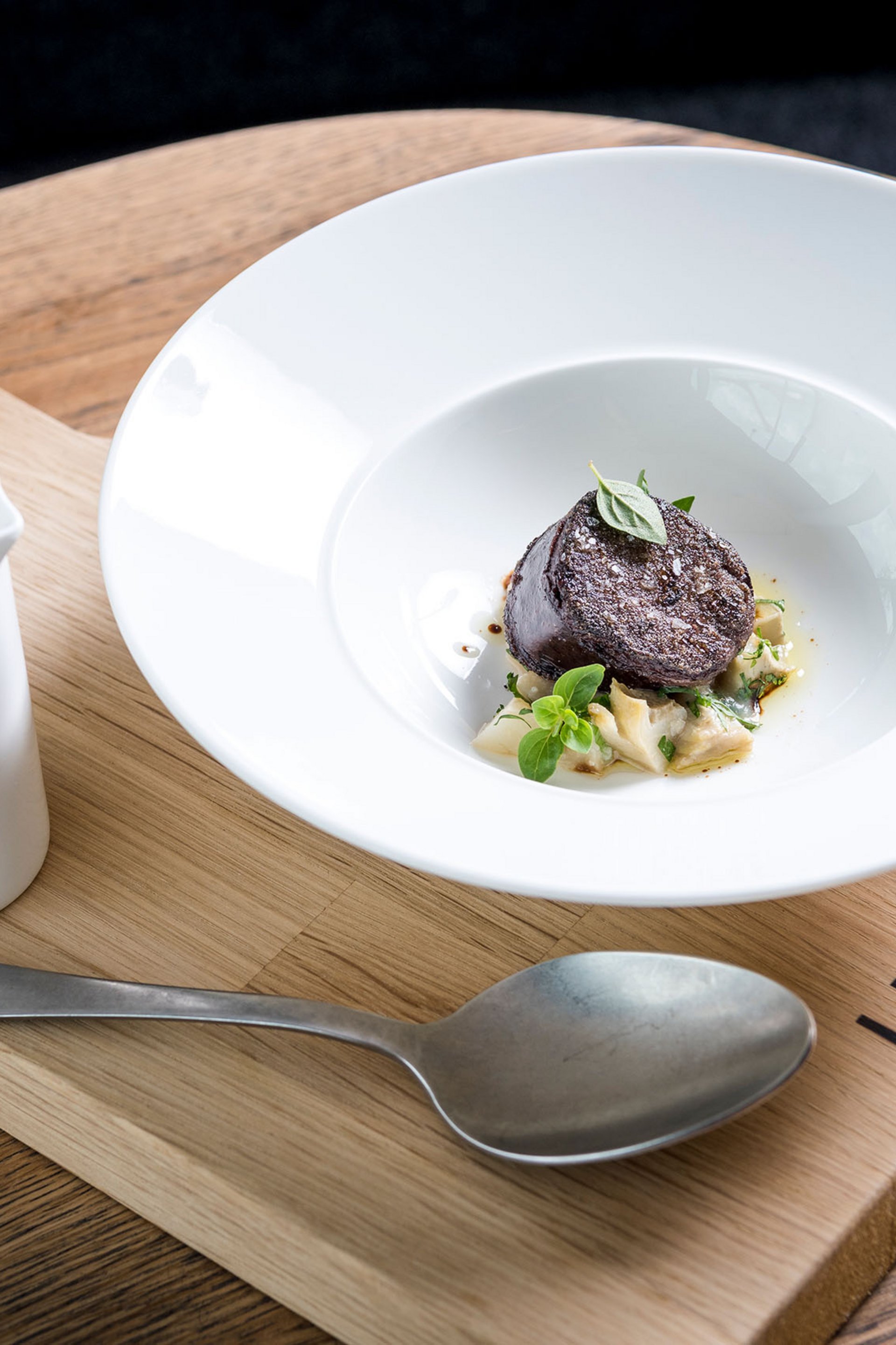 Fein angerichtete Gourmet-Speise mit Sauce, serviert auf Holzbrett im Lumi Restaurant