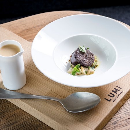 Fein angerichtete Gourmet-Speise mit Sauce, serviert auf Holzbrett im Lumi Restaurant