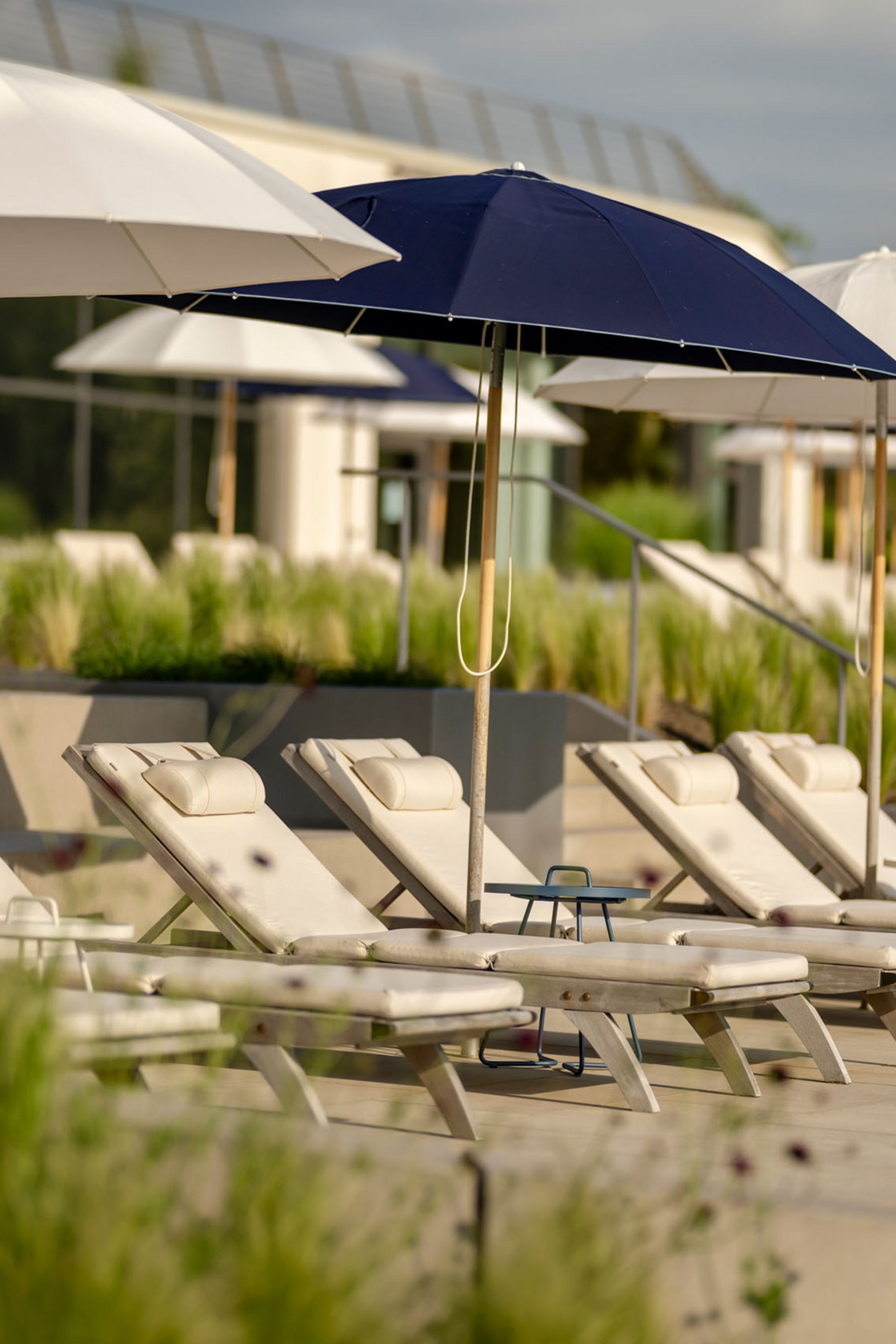 Chaises longues vides avec parasols dans une zone de piscine ensoleillée