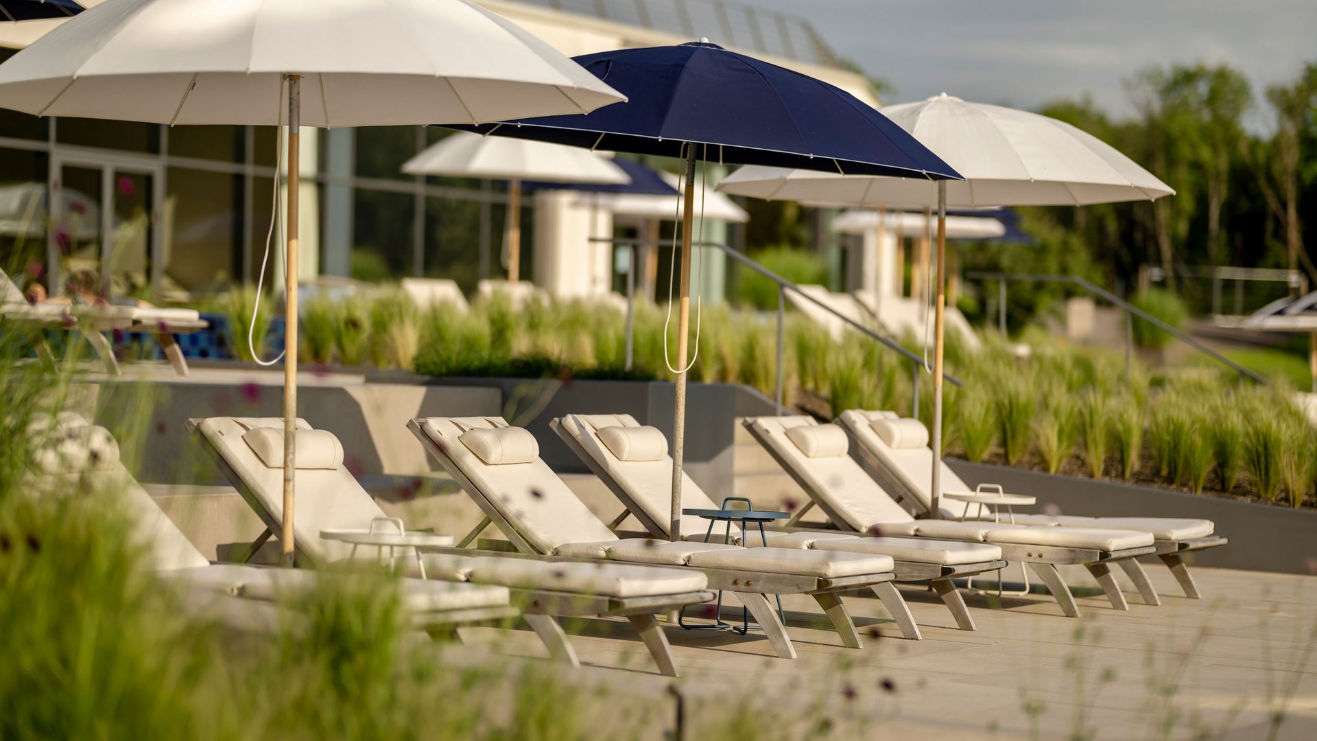 Chaises longues vides avec parasols dans une zone de piscine ensoleillée