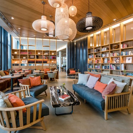 Moderne Bibliothek mit gemütlichen Sofas, Holzregalen und Hängelampen