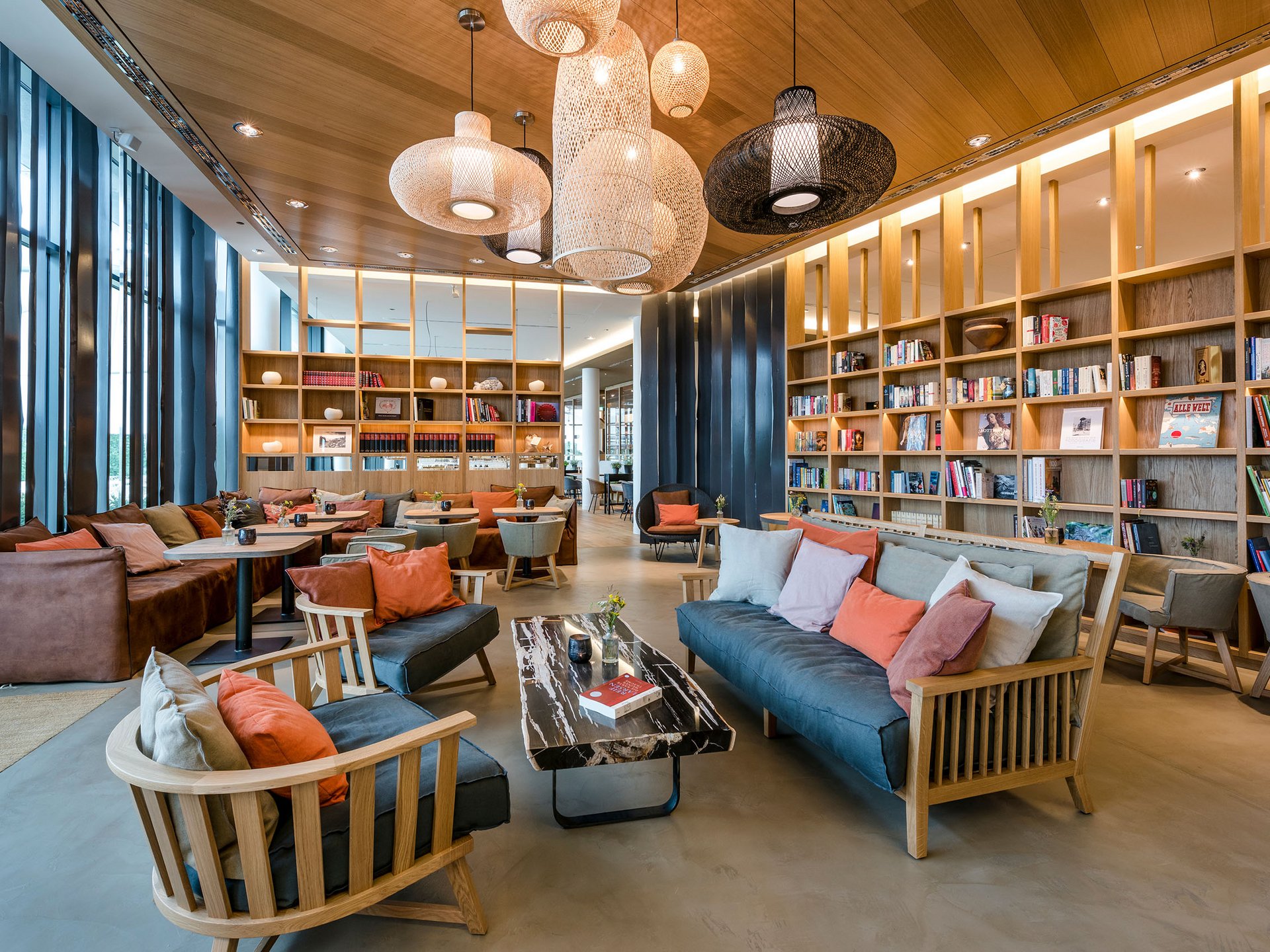 Moderne Bibliothek mit gemütlichen Sofas, Holzregalen und Hängelampen