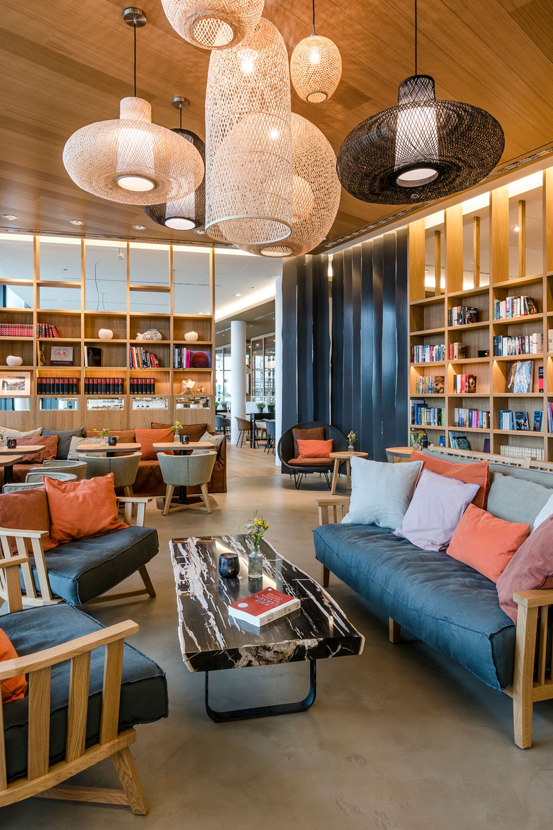 Moderne Bibliothek mit gemütlichen Sofas, Holzregalen und Hängelampen