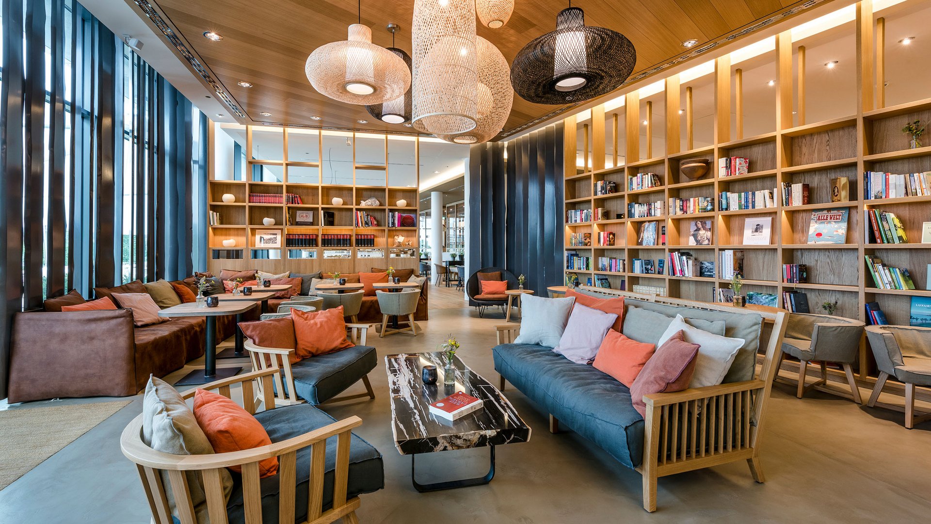 Bibliothèque moderne avec canapés confortables, étagères en bois et suspensions
