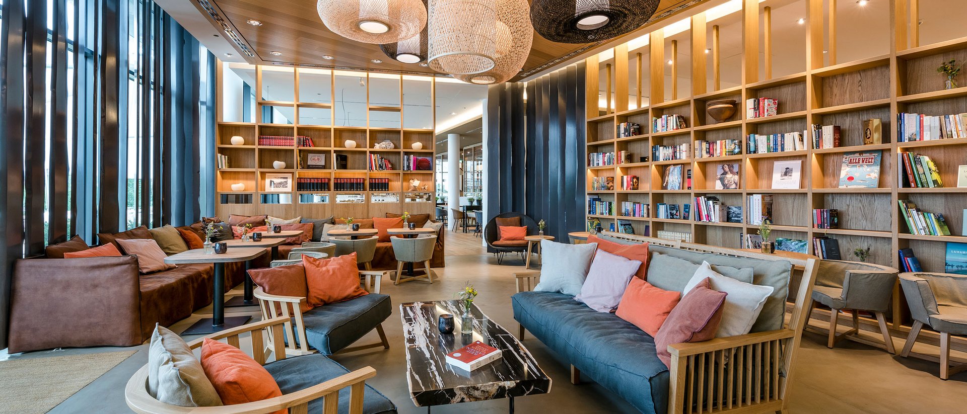 Moderne Bibliothek mit gemütlichen Sofas, Holzregalen und Hängelampen
