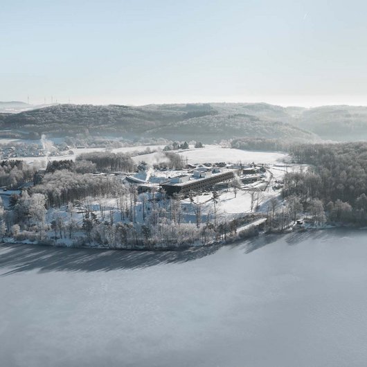 Luftaufnahme einer verschneiten Halbinsel mit Gebäuden inmitten eines zugefrorenen Sees