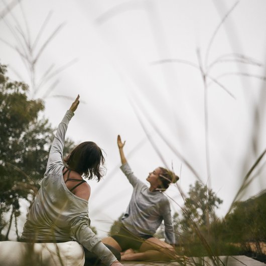 Two women doing yoga outdoors on a mat