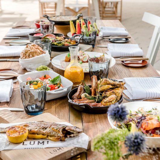 Essensauswahl auf einem Holztisch mit gebratenem Fisch, Fleisch und Salaten