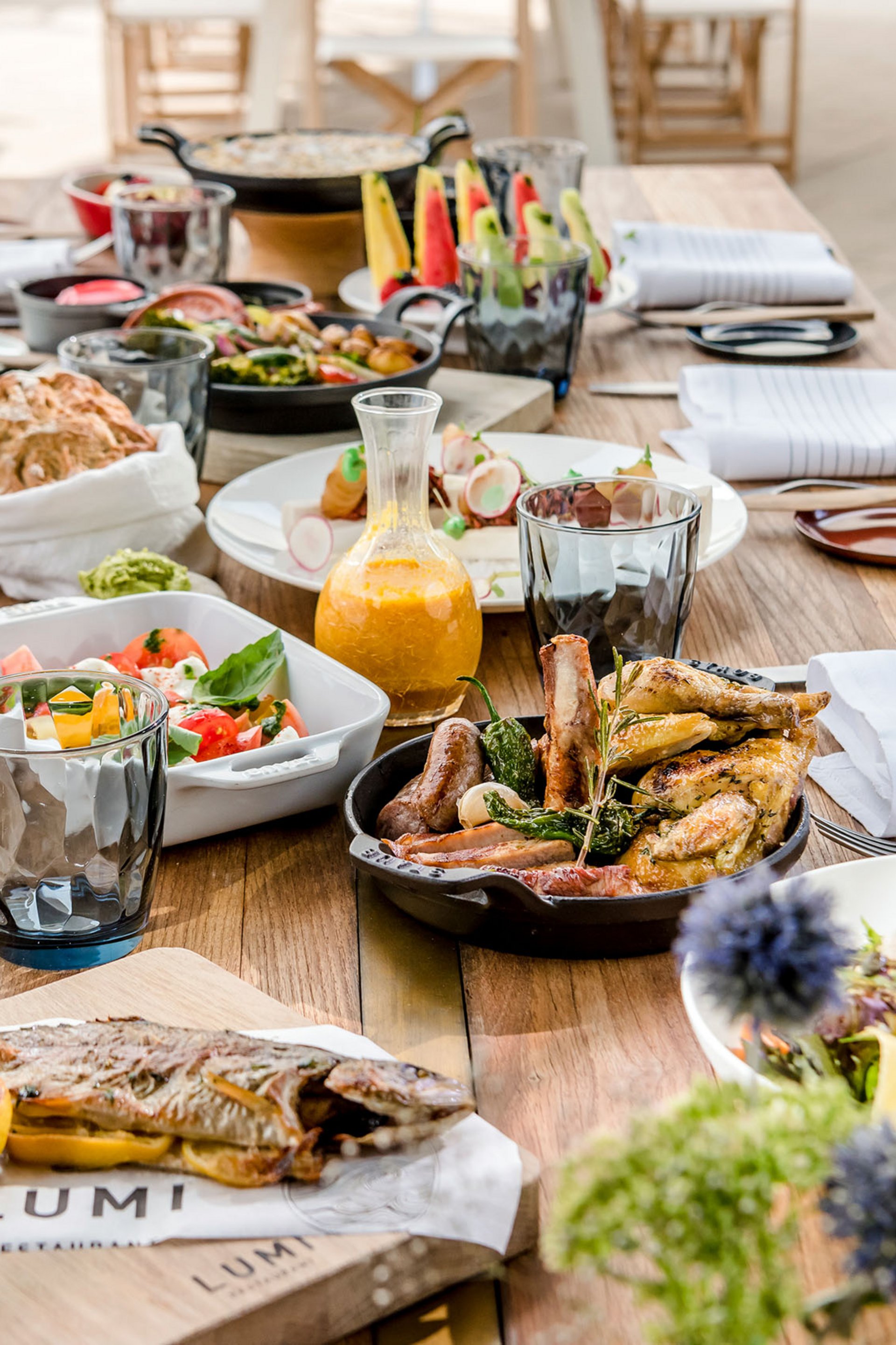 Table en bois dressée avec poisson grillé, viande et salades variées