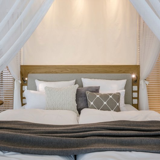 Cozy bathroom bed with pillows, blanket, and wooden furniture